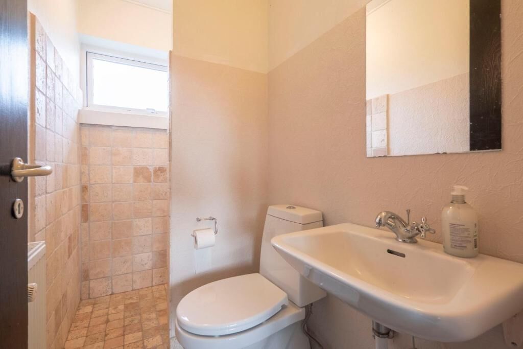 Et badeværelse med toilet, vask og spejl.