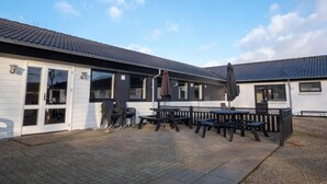 Ein Gebäude mit einer Terrasse, Sitzgelegenheiten im Freien und einem überdachten Bereich.