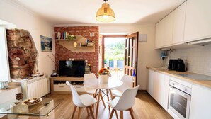 A modern kitchen with white cabinets, a brick fireplace, and a dining area with white chairs.