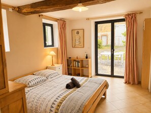 Ein Schlafzimmer mit einem Bett, einem Nachttisch, einem Bücherregal und einer Schiebetür zu einer Terrasse.
