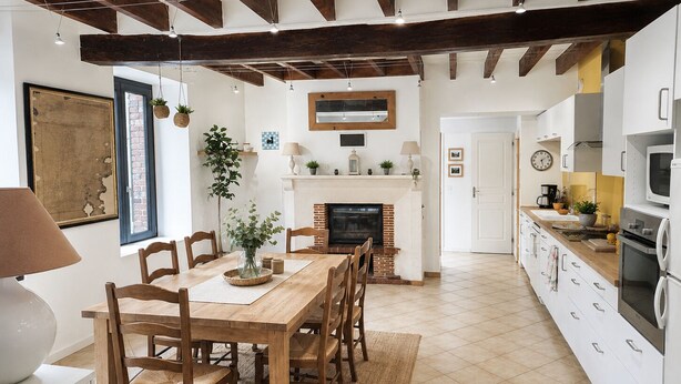 A kitchen with white cabinets, a wooden dining table, and a fireplace. - Charming country house in a flower garden between Paris and Chartres (Yermenonville)