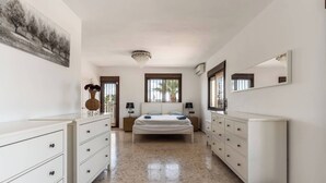 A bedroom with a bed, two nightstands, a dresser, a mirror, and a painting on the wall. - The Padel Villa (Pinos de Alhaurín)