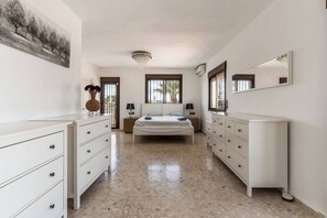 Een slaapkamer met een bed, twee nachtkastjes, een dressoir, een spiegel en een schilderij aan de muur.
