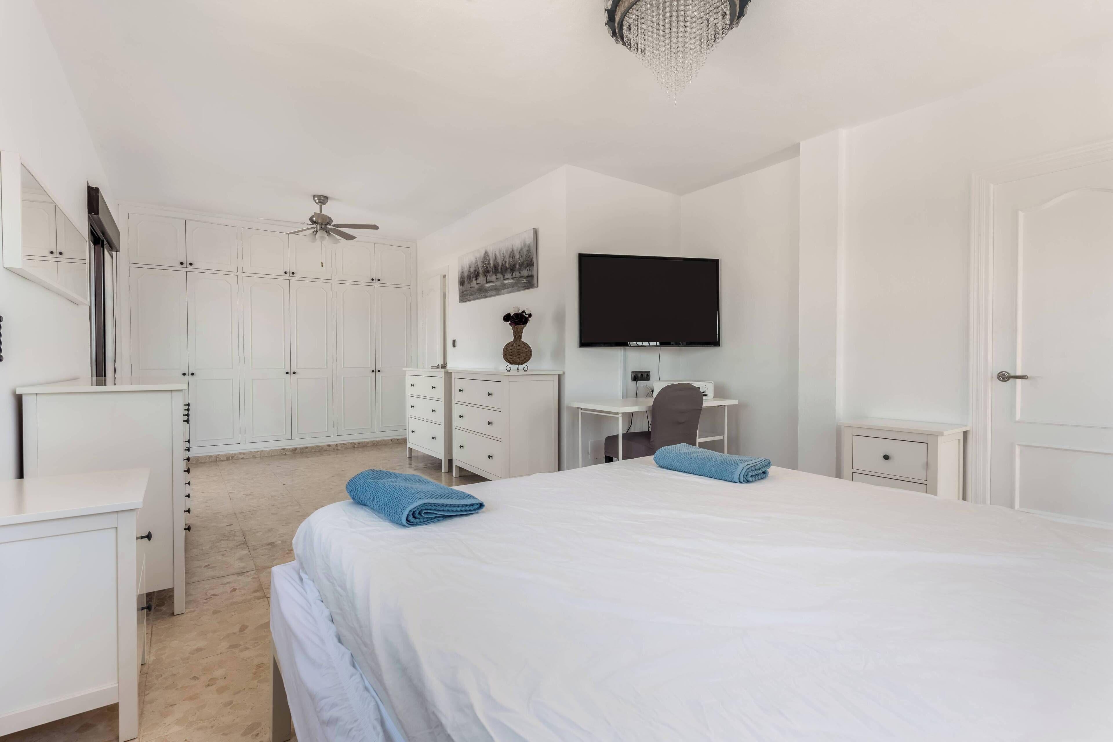 Une chambre d’hôtel comprenant un lit, un bureau, une chaise, une télévision et une armoire.