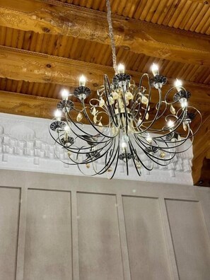 A chandelier with multiple arms and lights, hanging from a wooden ceiling.