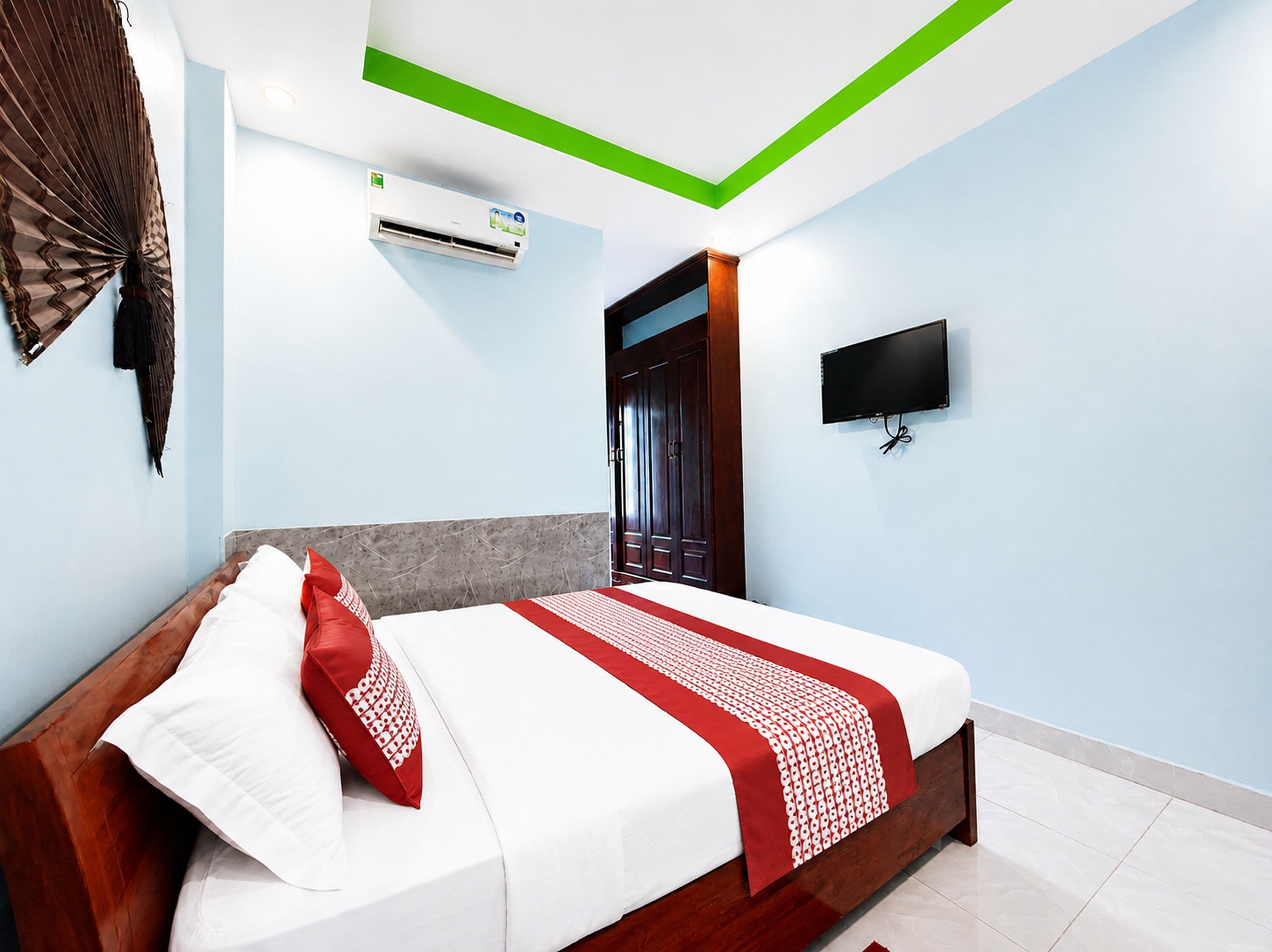 A bedroom with a bed, a TV, an air conditioning unit, and a door.