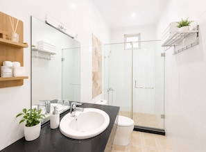 A modern bathroom with a large mirror, a sink, a toilet, and a glass-enclosed shower. - Palette Anh Vu Hotel Phu Quoc (Phu Quoc)