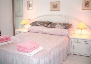 Ein Schlafzimmer mit einem Bett, zwei Nachttischen, einer Kommode und einem Fenster.