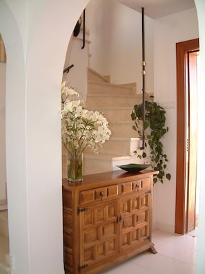 Ein Holzkabinett mit Schubladen, eine Vase mit weißen Blumen und eine Topfpflanze.