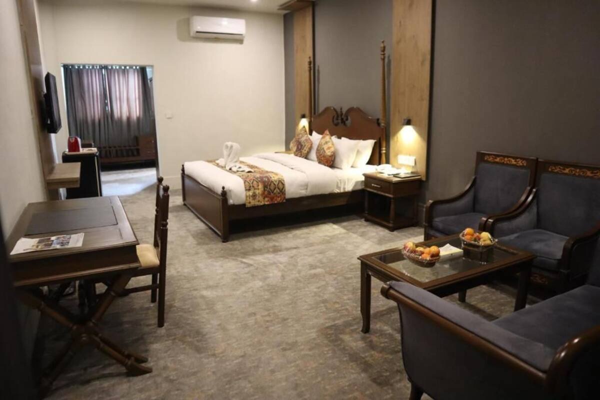 Una habitación de hotel con cama, escritorio, silla, sofá y mesa de centro.