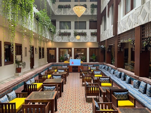 A courtyard with seating, a television, and hanging plants. - Destination Heritage Peshawar (Peshawar)