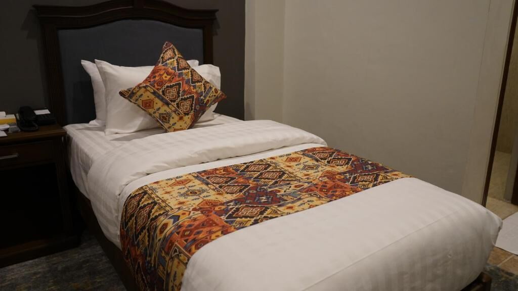A hotel room with a bed, a nightstand, and a telephone.
