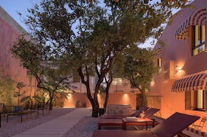 Un patio con un árbol, sillones de descanso y una chimenea de piedra.