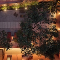 Terraza en la azotea con piso de grava, plantas en macetas y una zona de estar con cojines a rayas.