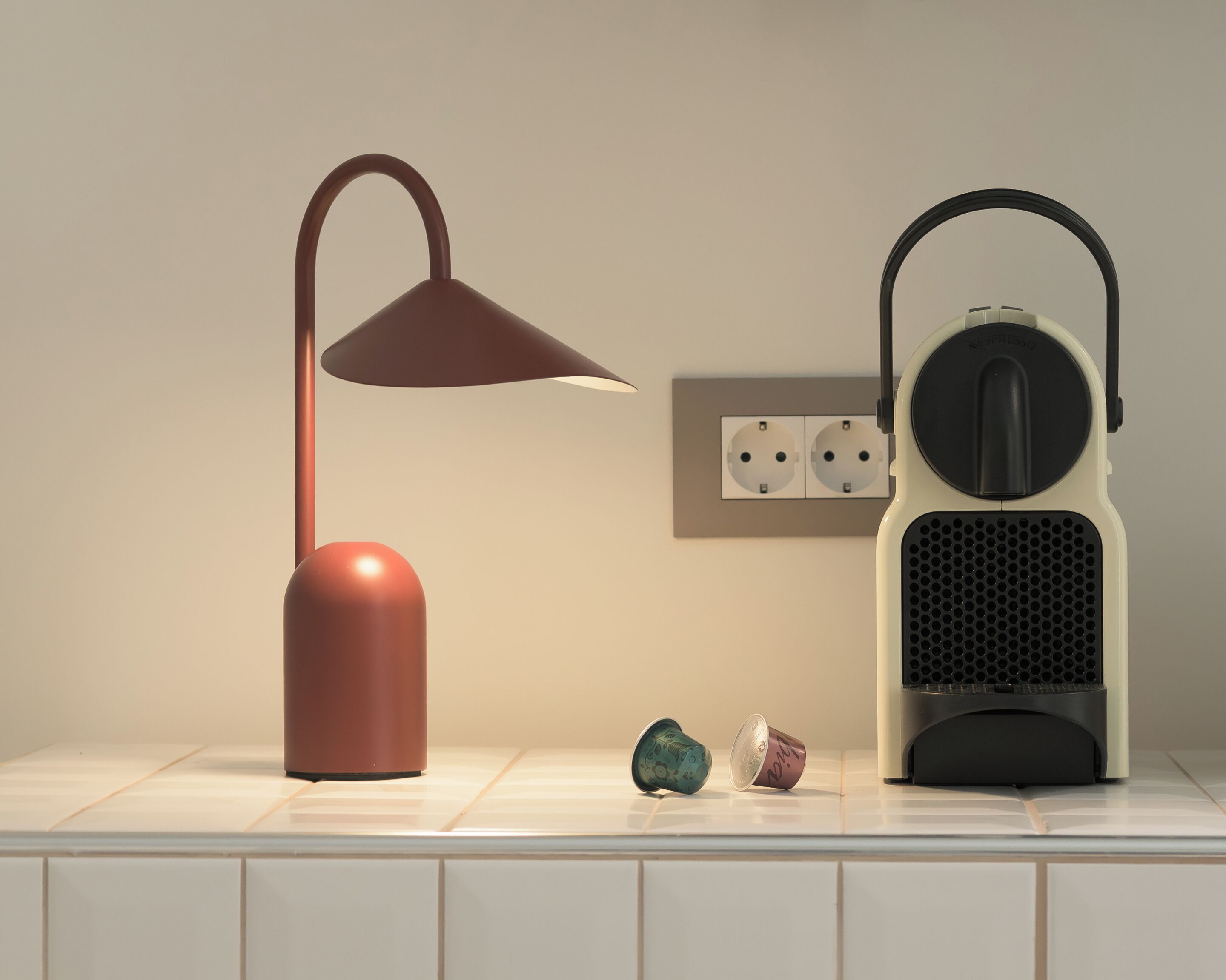 A lamp and a speaker on a white tiled surface.