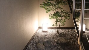 Ein Zimmer mit einem kleinen Baum, einer Lampe und einer Treppe.