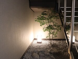 Una habitación con un árbol pequeño, una lámpara y una escalera.