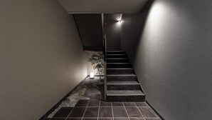 Eine moderne Treppe mit minimalistischem Design, einer kleinen Pflanze und einer Lichtquelle oben.