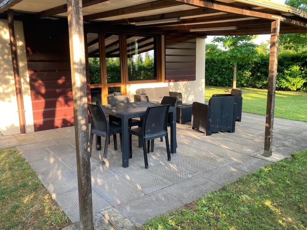 Eine Terrasse im Freien mit Tisch und Stühlen, einem Grill und einem überdachten Bereich mit Blick auf den Garten.