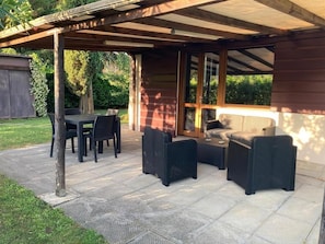 An outdoor patio with a table and chairs, a sofa, and a small table.