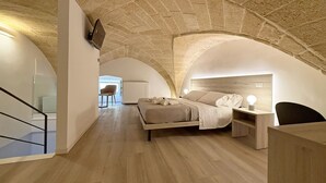 A bedroom with a stone vaulted ceiling, a bed, a bedside table, and a chair. - Molo Mazzini (Gallipoli)