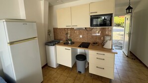 Una cocina compacta con refrigerador, microondas, pileta y un pequeño bote de basura.