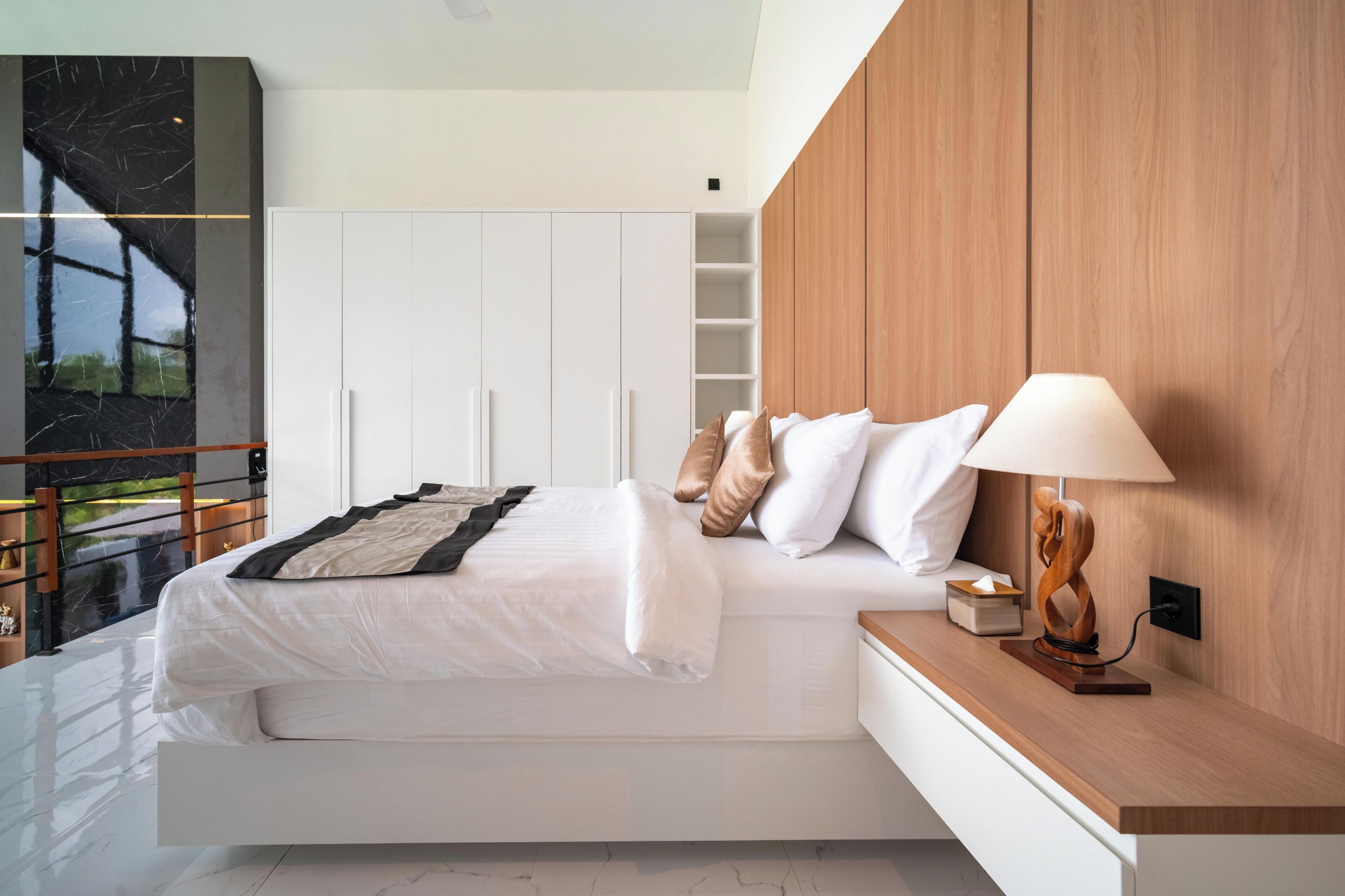 Une chambre moderne avec un lit, une table de chevet, une lampe et une grande fenêtre donnant sur un beau paysage.