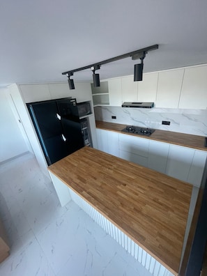 Eine moderne Küche mit weißen Schränken, einer Holz Arbeitsplatte und integrierten Geräten.