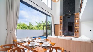Comedor con una mesa lista para seis comensales, piscina y zona de estar con vistas a zonas verdes.
