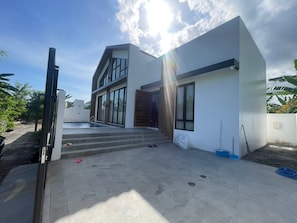 Een modern huis met een zwembad, een trap die naar de ingang leidt, en een heldere lucht.