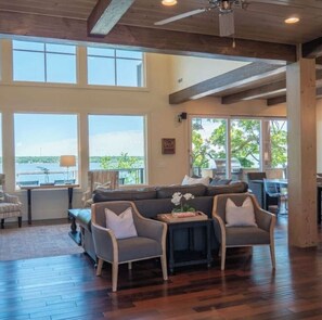 A spacious living room with a large sectional sofa, two armchairs, a coffee table, and a view of the outdoors through large windows.