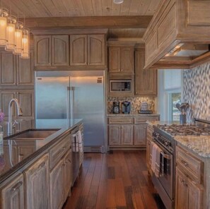 A kitchen with wooden cabinets, a stainless steel refrigerator, a microwave, a coffee maker, and a gas stove.