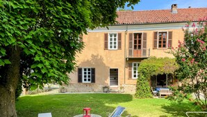 Uma casa com jardim, uma mesa com cadeiras e uma árvore.