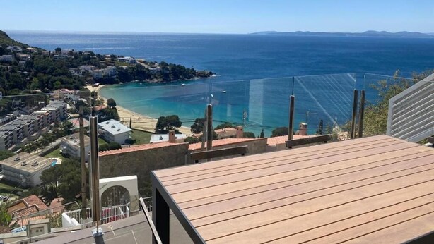 Vista costera desde un punto elevado con vistas a una playa y zona residencial.