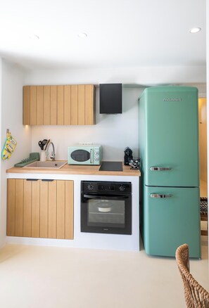 Eine kleine Küche mit Holzausstattung, einem grünen Kühlschrank, einer Mikrowelle und einem Geschirrspüler.