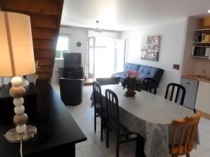 Un comedor con una mesa, sillas, una lámpara, televisor y un sofá.