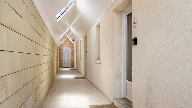 A corridor with tiled walls, a door at the end, and a small window.