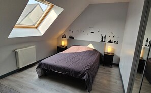Quarto com claraboia, cama, mesas de cabeceira com abajures, radiador e adesivos de parede.