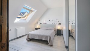 A bedroom with a skylight, a bed, bedside tables, and a radiator. - Gîte des Pluviers – Modern Villa Near the Beach in Saint-Martin-de-Bréhal (Bréhal)