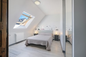 Een slaapkamer met dakraam, een bed, nachtkastjes en een radiator.