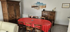 Uma área de jantar com uma mesa redonda, cadeiras de madeira, um armário e obras de arte na parede.