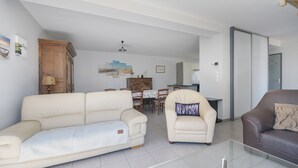 A spacious living area with a sofa, armchair, and a glass coffee table. - Gîte des Pluviers – Modern Villa Near the Beach in Saint-Martin-de-Bréhal (Bréhal)