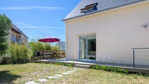 A modern house with a patio, a red umbrella, and a clear sky. - Gîte des Pluviers – Modern Villa Near the Beach in Saint-Martin-de-Bréhal (Bréhal)