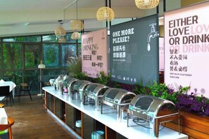 A buffet setup with food dispensers, a menu board, and a seating area with tables and chairs.