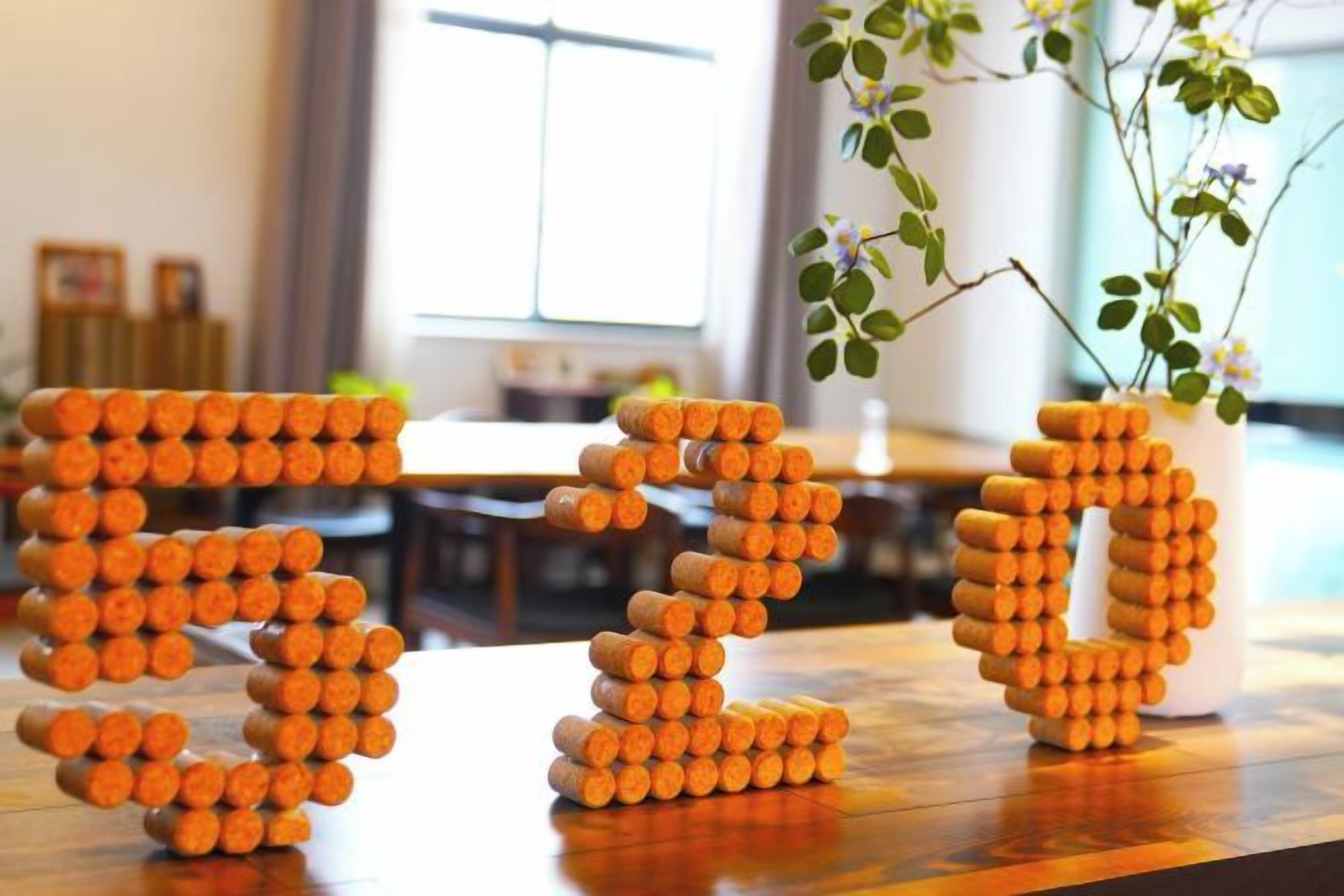 A wooden table with a decorative arrangement of orange cylindrical objects.