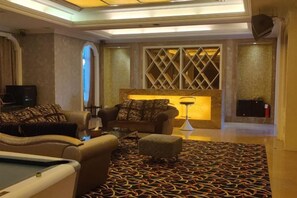 Un salon d’hôtel avec des canapés, une table de billard et une moquette à motifs.