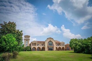 A large building with multiple arches and a tower, surrounded by greenery. - Eclat (Xuyi)