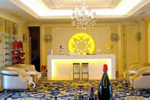A hotel lobby with a reception desk, seating area, and a chandelier.