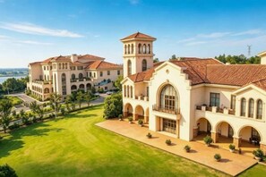A large, historic building with multiple wings and a central tower, surrounded by well-maintained lawns and a clear sky. - Eclat (Xuyi)