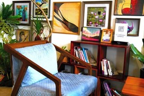 A room with a wooden chair, a bookshelf, and framed artwork on the wall. - Eclat (Xuyi)